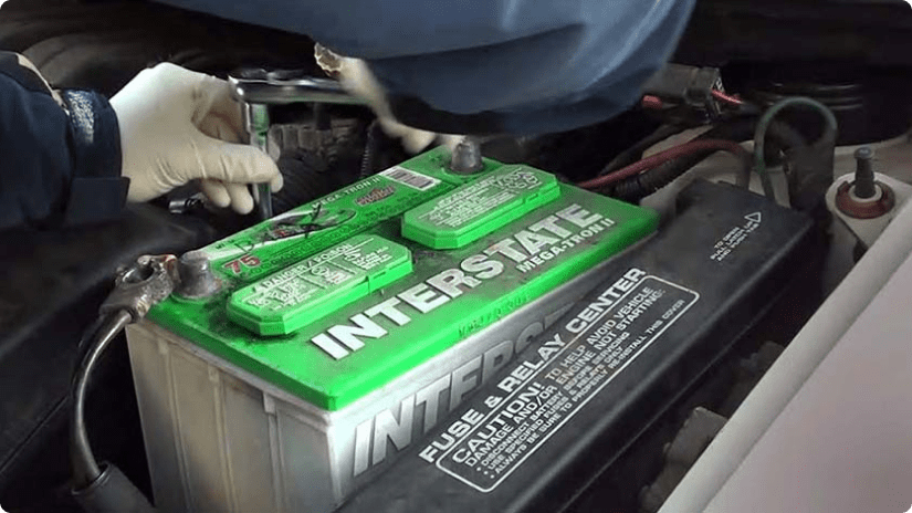 Technician using a socket wrench to loosen bolts to take out old battery