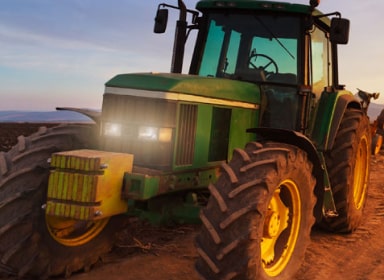 Unoccupied green tractor with headlights on.