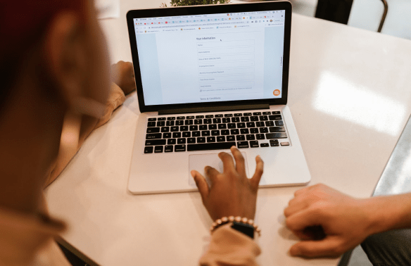 Two co-workers sitting at a table looking at a laptop screen