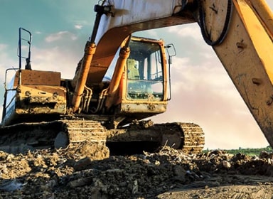 Unoccupied excavator on dirt terrain. Excavator claw dug into the ground.